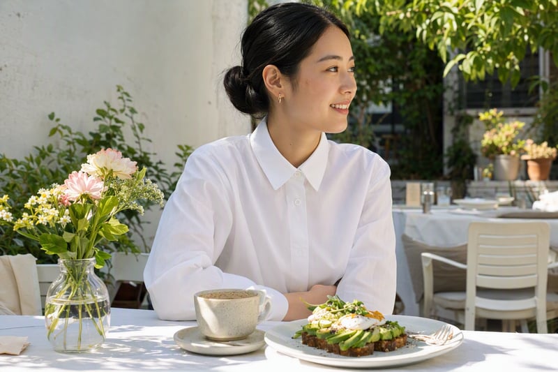 Woman in a white shirt at a sunlit brunch table, soft window light on her face
