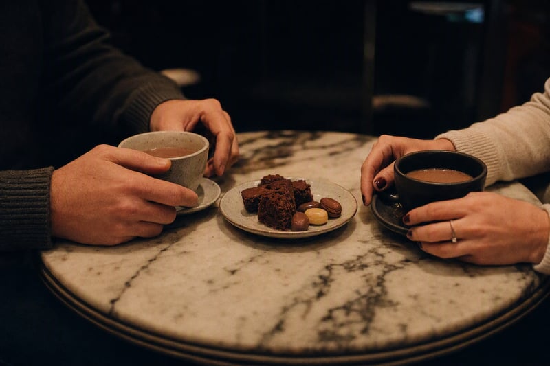 A hand and a wine glass lit by flash on a dark restaurant table, face out of frame