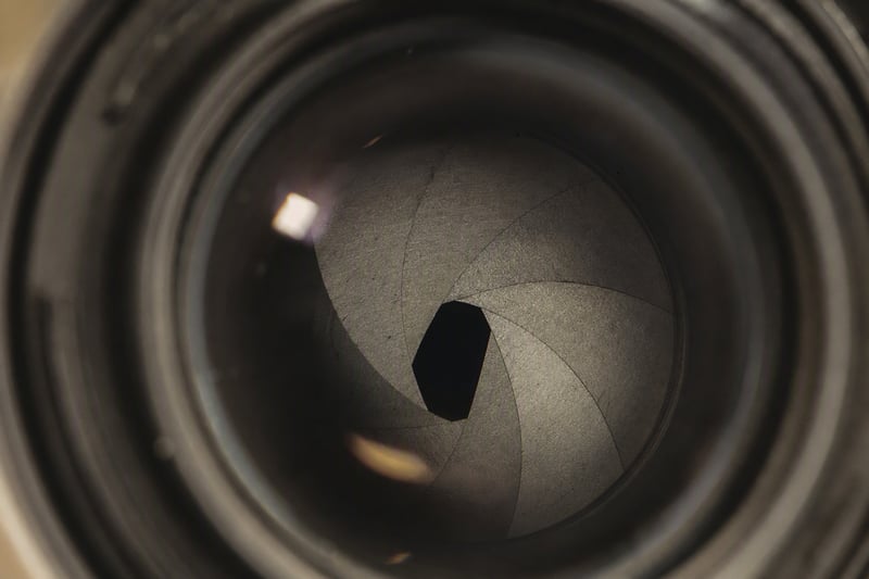 Close view of a phone camera module resting on a dark textured surface