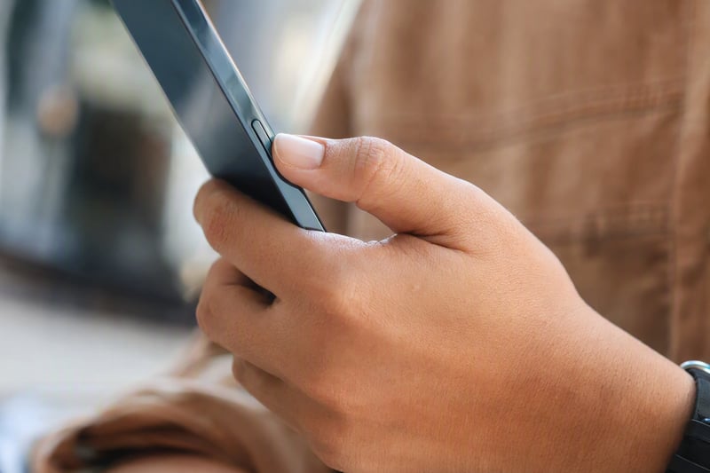 Thumb resting on the side button of a phone held horizontally in two hands