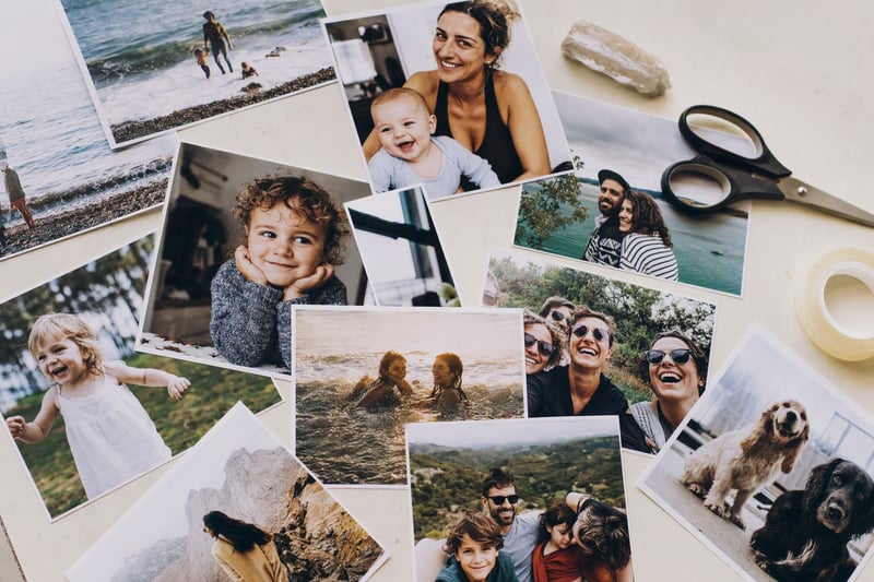 Printed photos arranged in a grid on a table beside a phone showing the layout