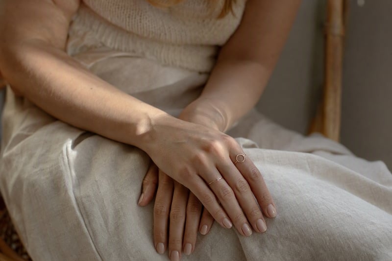 Hands resting lightly on a bag strap in soft daylight, fingers slightly curved