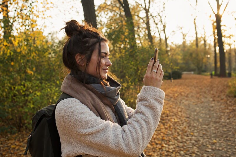 Woman photographing two friends across a cafe table in late afternoon light