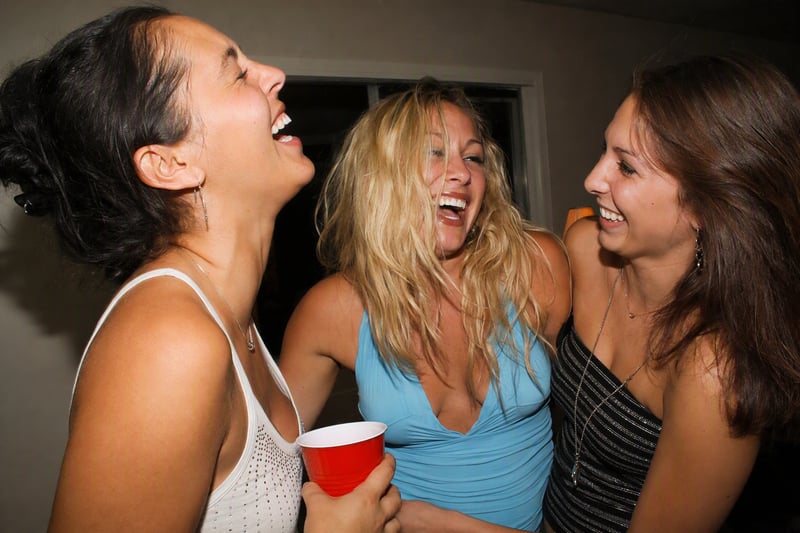 Group of friends squeezed onto a sofa at a house party lit by direct flash