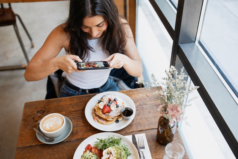 Phone showing a four-by-five crop of a portrait next to a laptop and notebook
