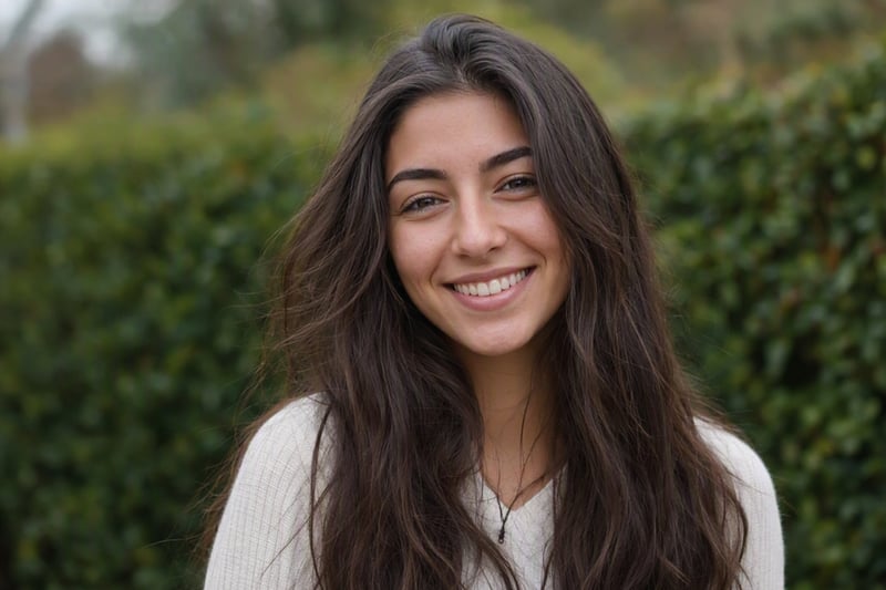Young woman photographed against a hedge with soft blurred greenery behind her