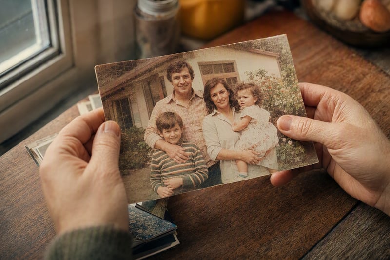 A faded family photograph lying next to a phone showing a restored version of it