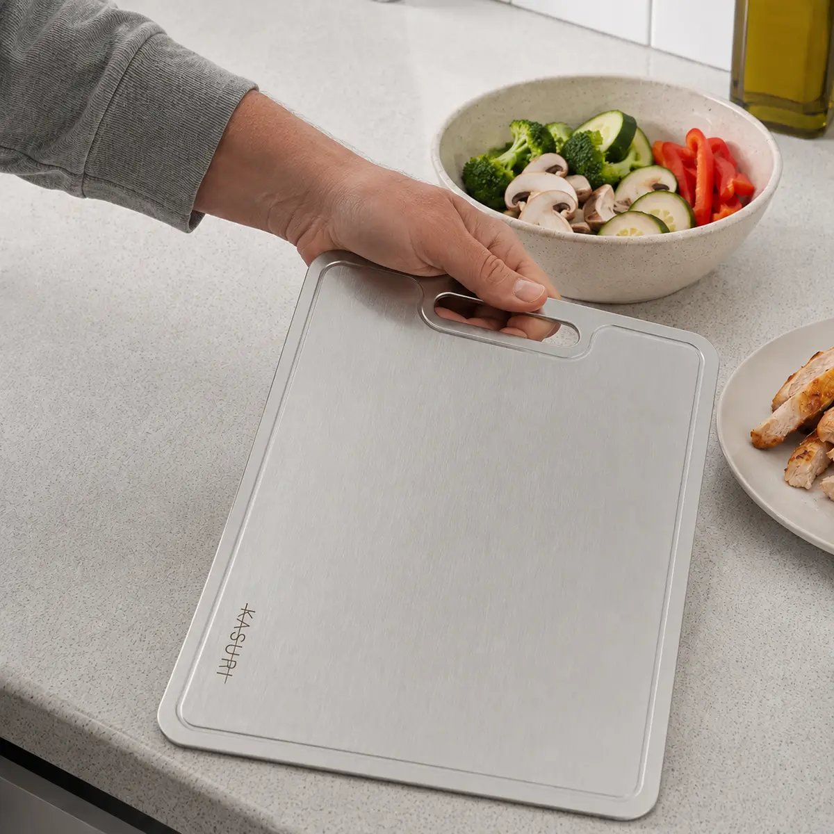 Planche à découper Kasuri sur le plan de travail avec un bol de légumes coupés