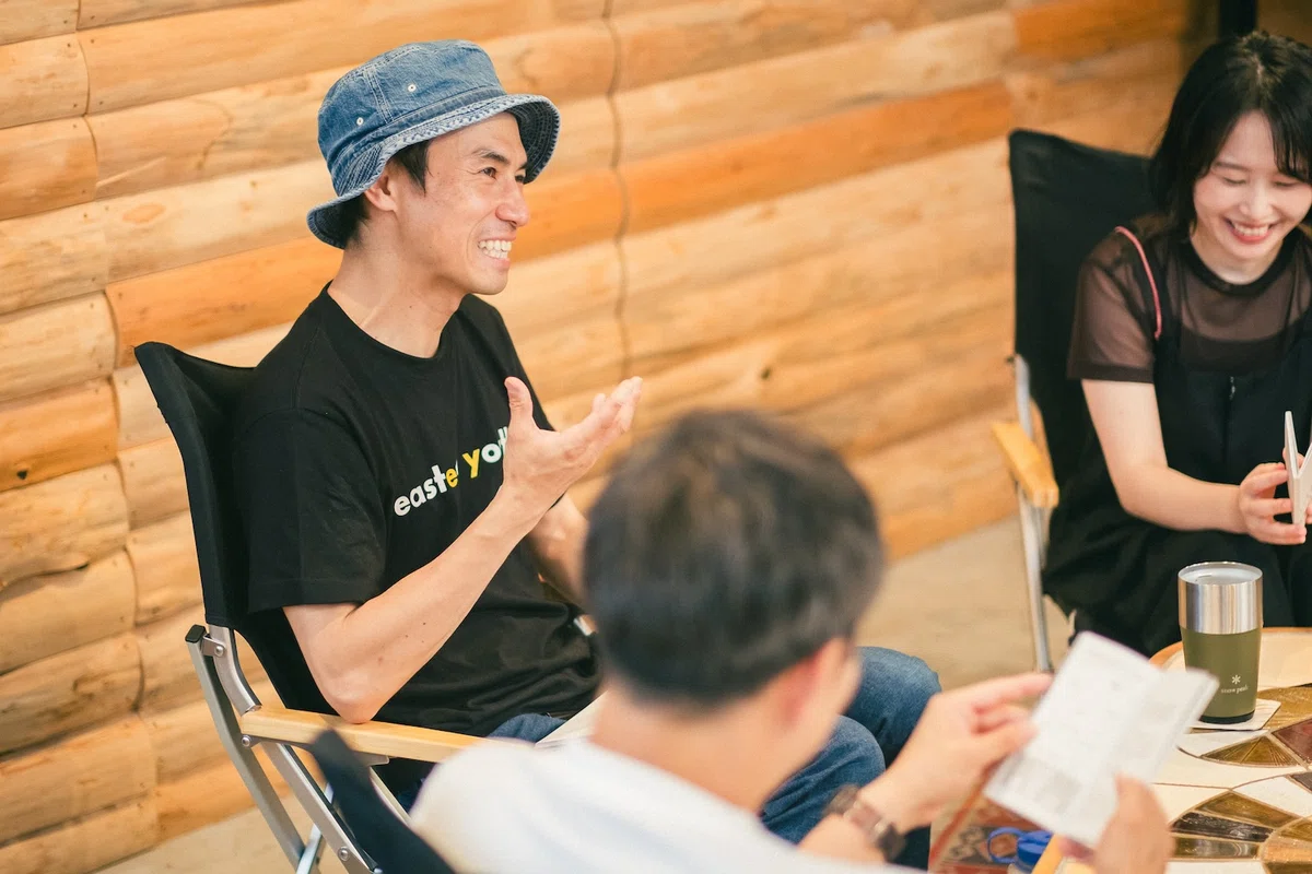 木の壁の部屋で参加者と話すヤマップ代表の春山慶彦さん
