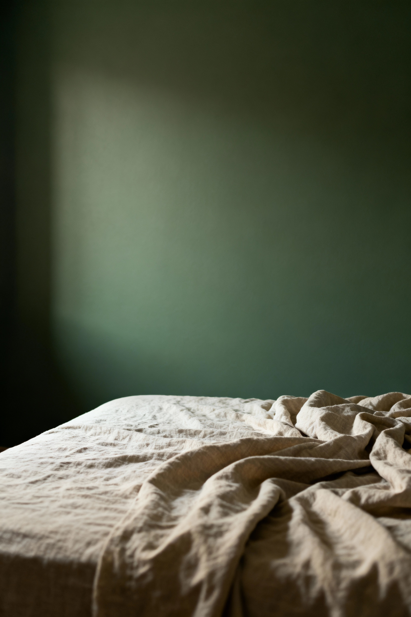 Bedroom wall painted in serene, matte sage green with natural light, embodying deep color resonance and liberation from transient trends for a tranquil sanctuary.