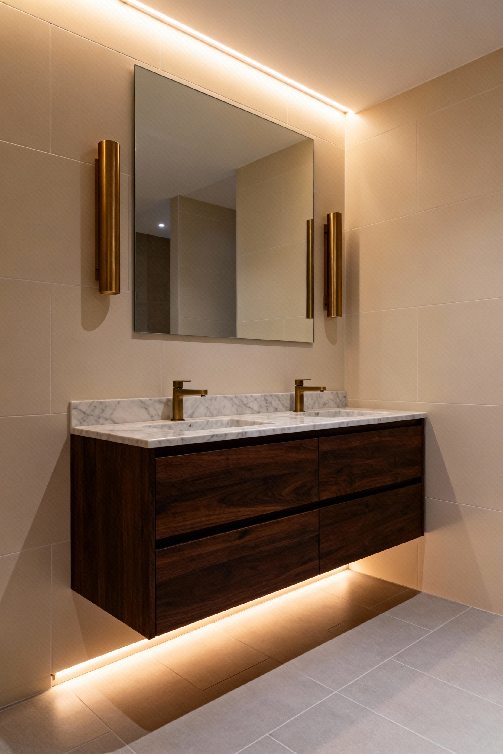 A photograph of a luxury bathroom featuring layered warm 2700K lighting from perimeter coves, vertical brass sconces, and under-vanity toe-kicks, showcasing a tranquil, spa-like atmosphere.