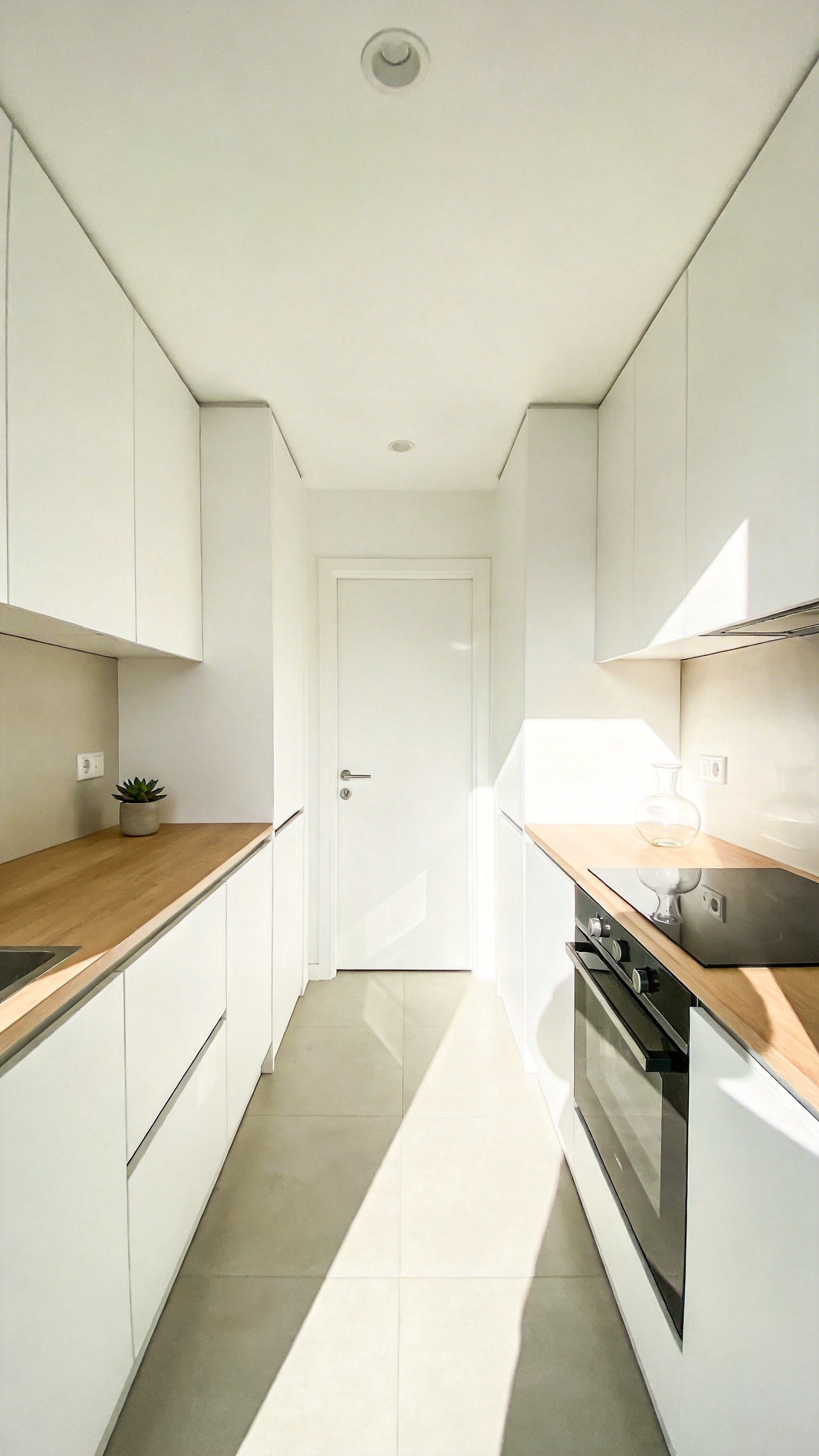 A bright and airy small apartment kitchen featuring light-reflecting matte gallery white walls and minimalist decor.
