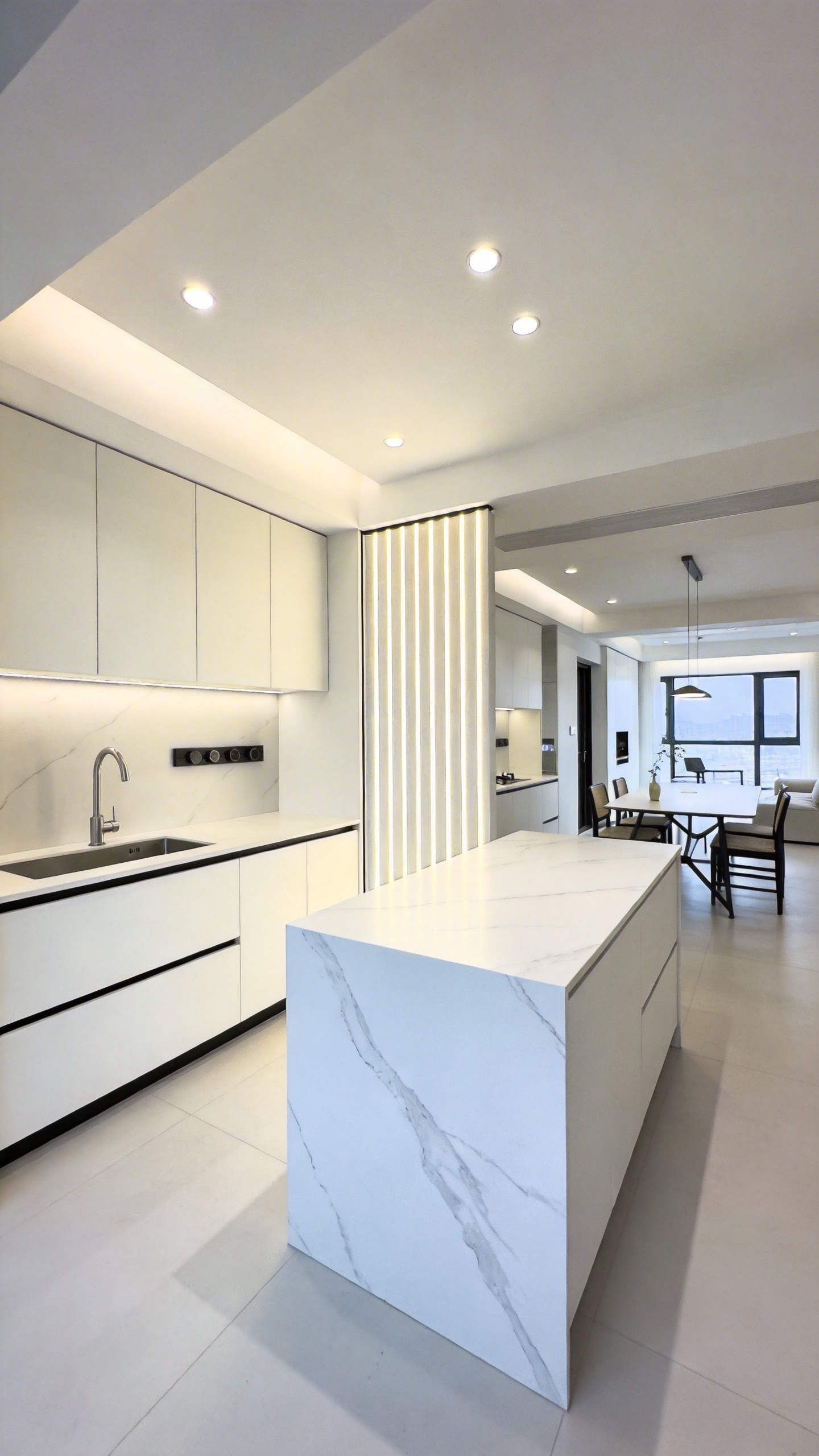 A minimalist white kitchen with architectural downlighting creating a light curtain partition between zones.