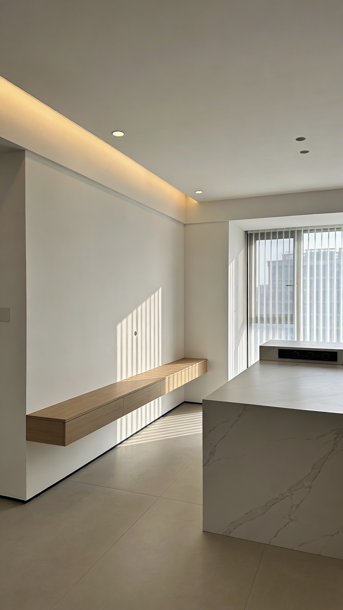 A minimalist white kitchen design featuring expansive white walls and the Japanese concept of Ma with a marble island and natural wood accents.