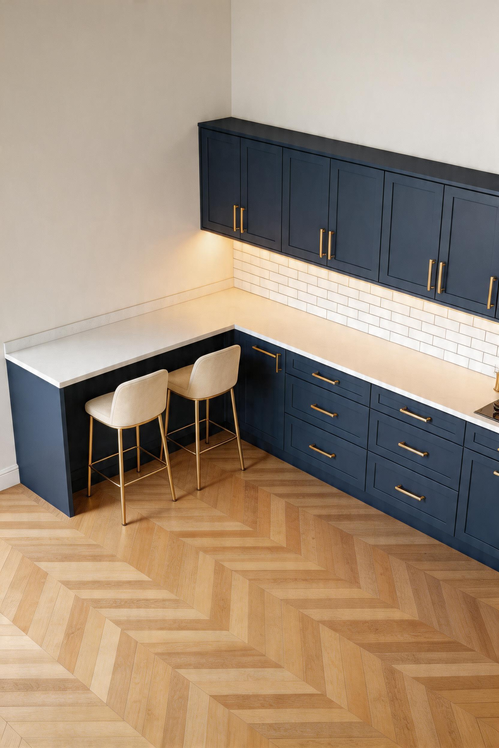 An L-shaped corner kitchen bar in navy blue turns a layout problem into a design asset — two people seated in a naturally conversational arrangement, both facing the kitchen.