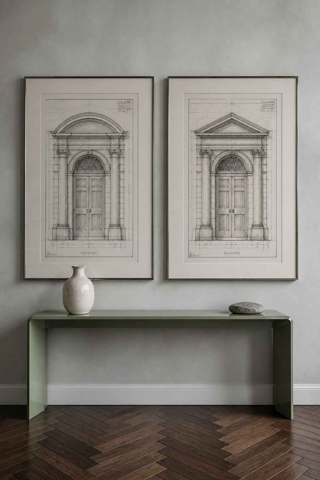 Two architectural elevation drawings in float-mount linen-mat frames turn a grey plaster wall into a quiet study in precision and restraint.