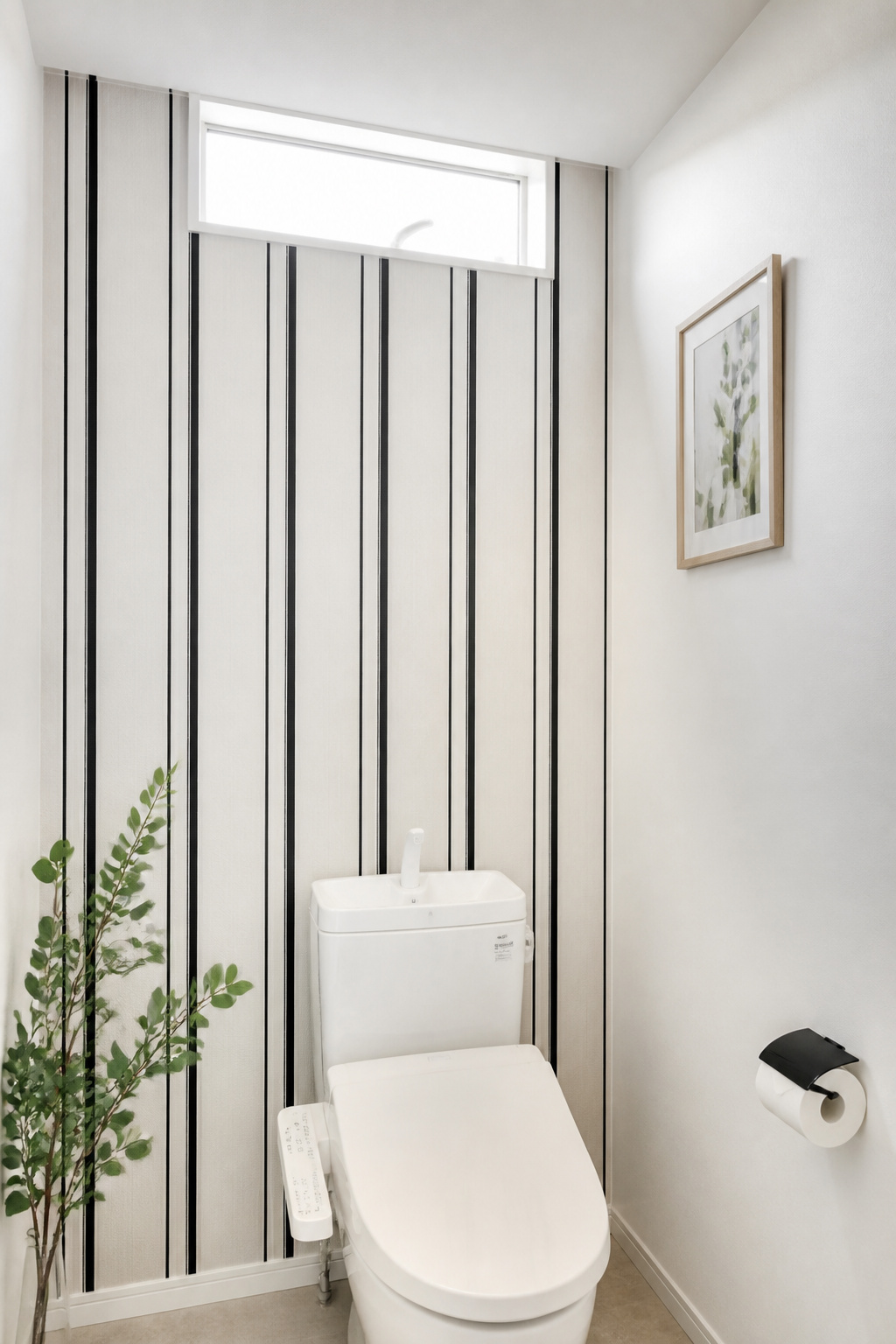 A geometric washi tape accent treatment on the wall behind a toilet — parallel vertical stripes creating a contemporary pattern that's entirely renter-safe and costs under $15 to install.