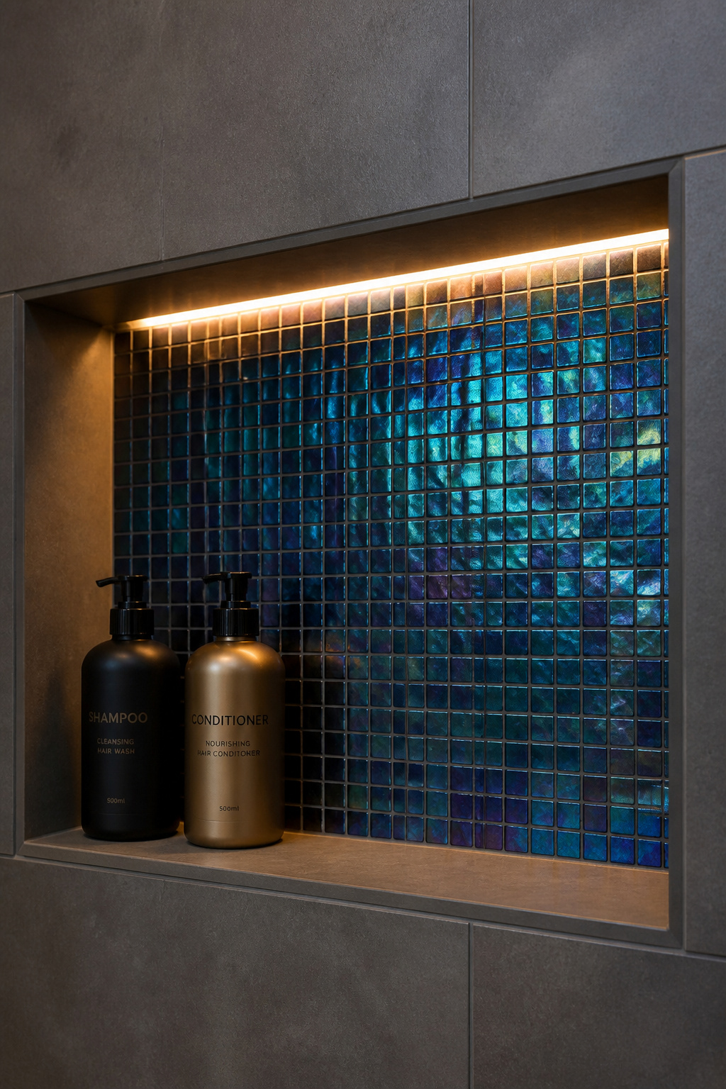 Iridescent glass mosaic in a shower niche — a small tile format used precisely where its flexibility and light-catching quality create maximum impact for minimum tile area.