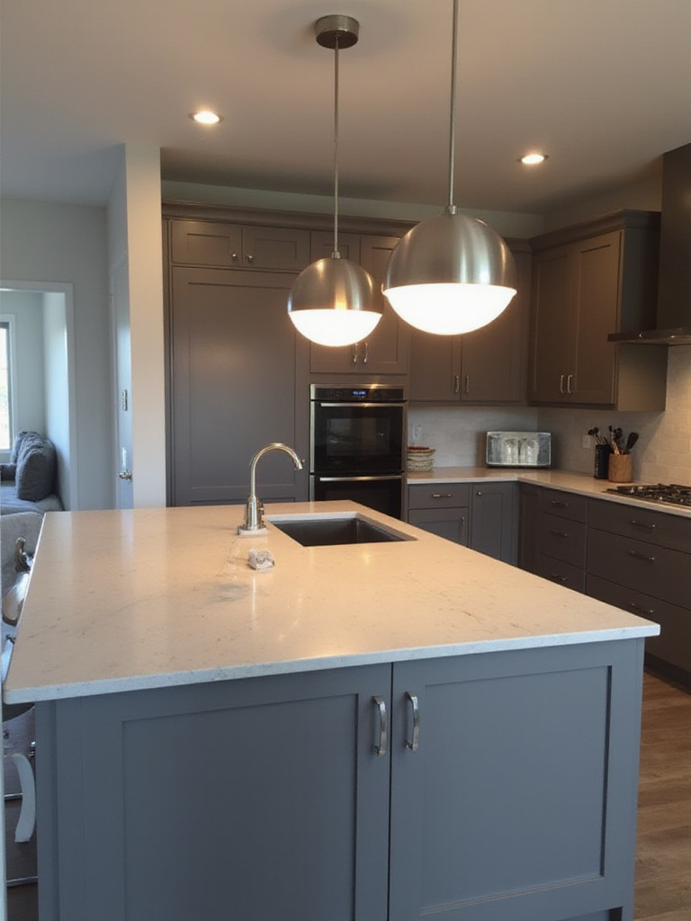Modern kitchen island with three brushed steel pendant lights.