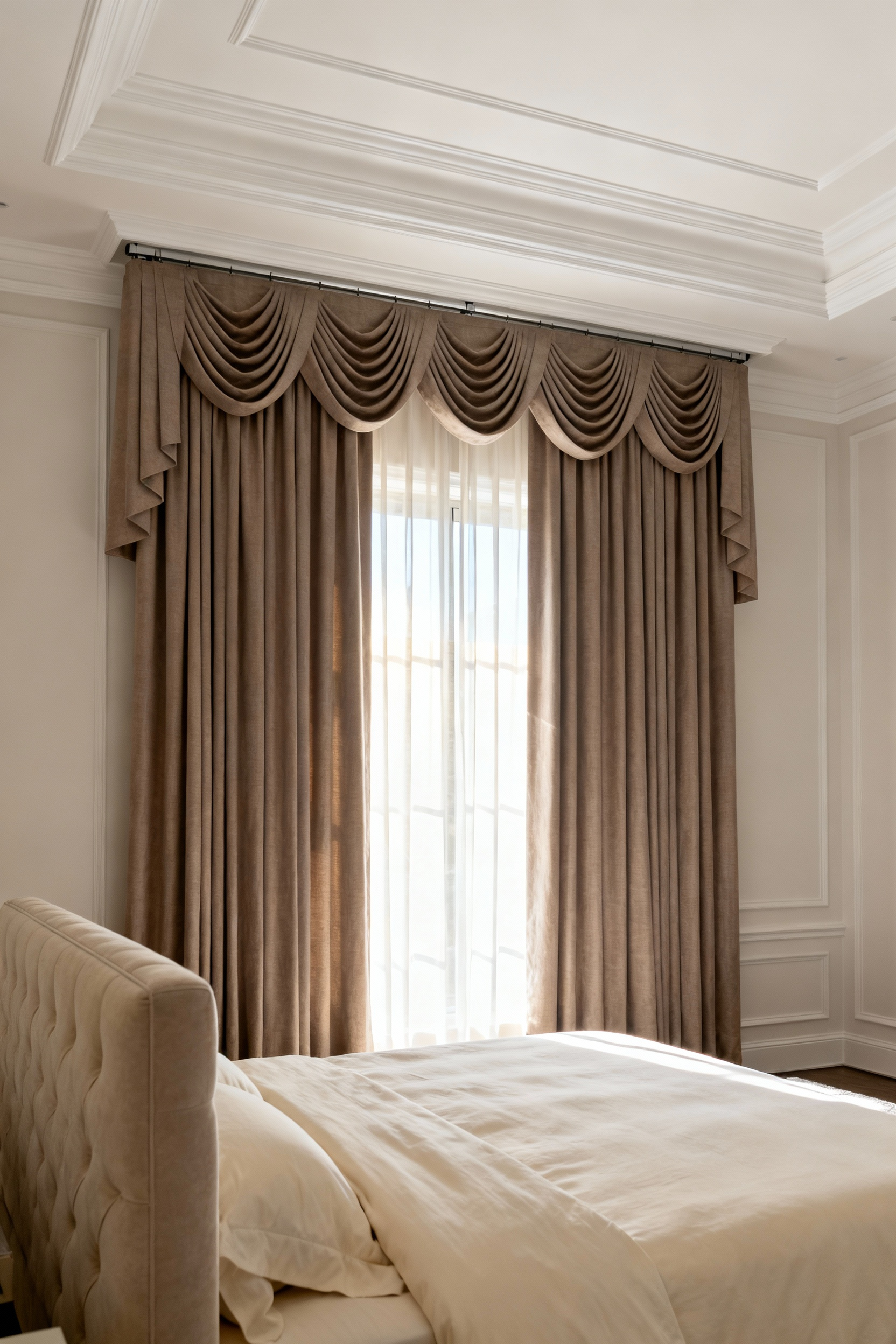 Floor-to-ceiling taupe linen drapery mounted directly beneath crown molding in a luxury bedroom to create an illusion of greater room height and architectural grandeur.