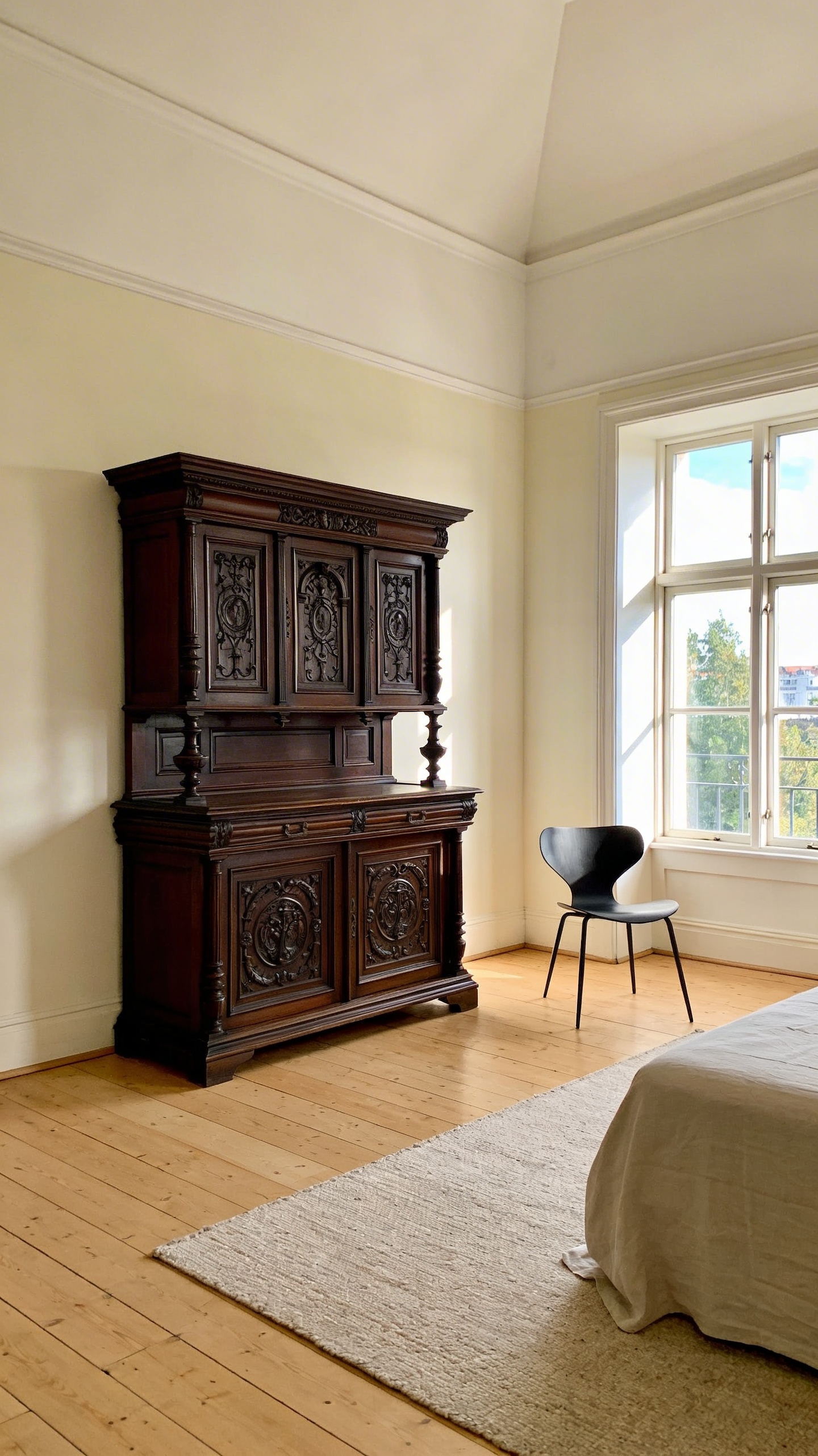 A vintage aesthetic bedroom interior showcasing a large Victorian mahogany armoire next to a thin-legged modern chair for spatial balance.