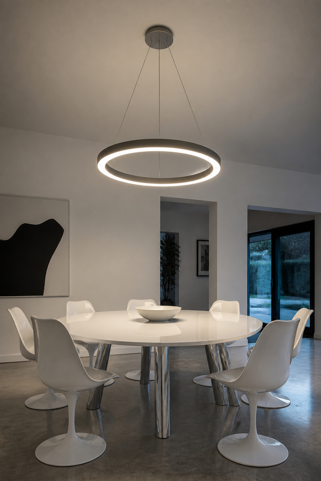 A continuous LED ring at 3000K illuminates a minimalist white dining room evenly and sits closer to the ceiling than traditional pendants — right for eight-foot ceilings.