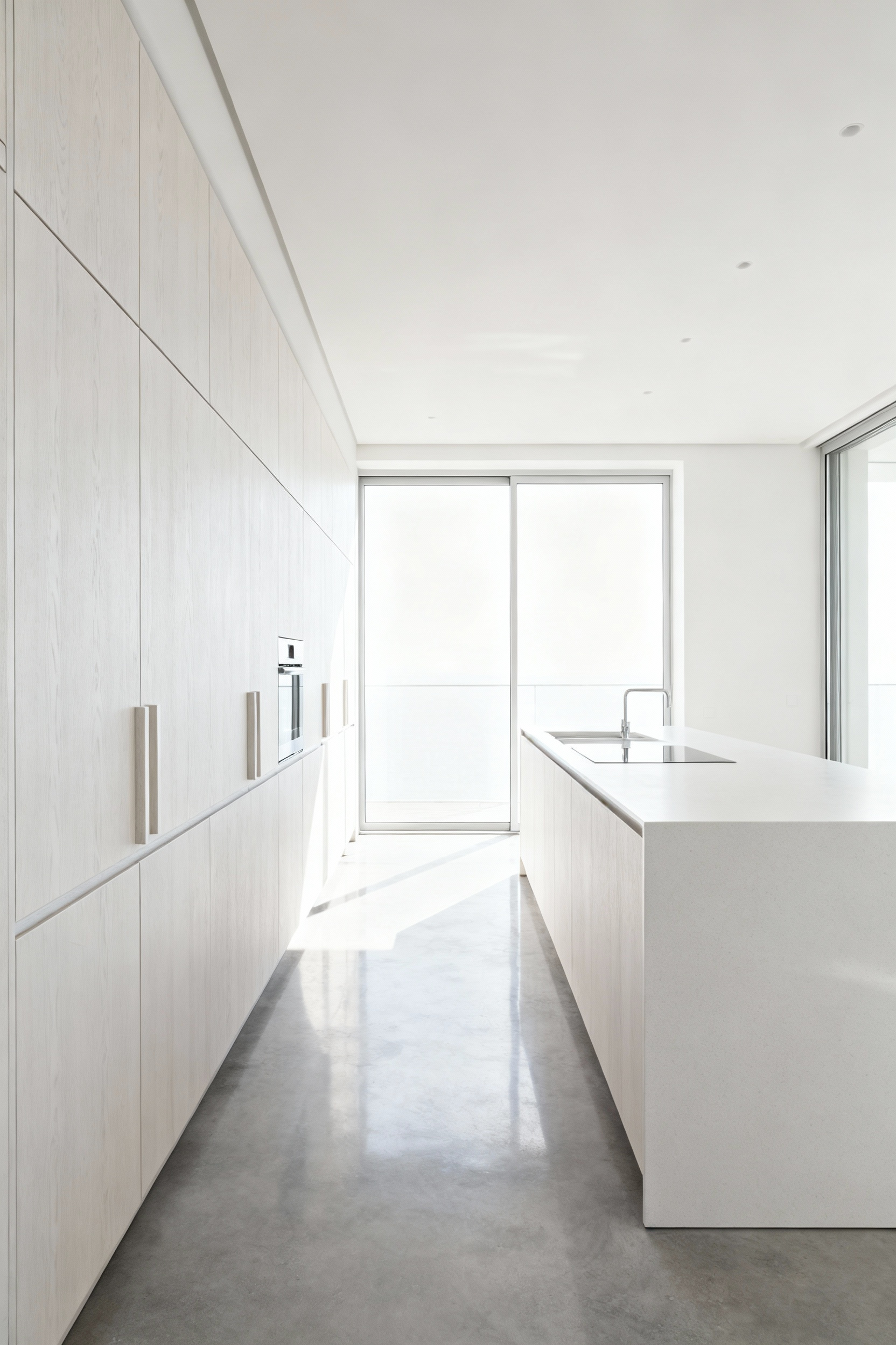 Scandinavian kitchen with integrated white-pigmented ash cabinets, concrete floor, and quartz countertop, showing seamless surface transitions.