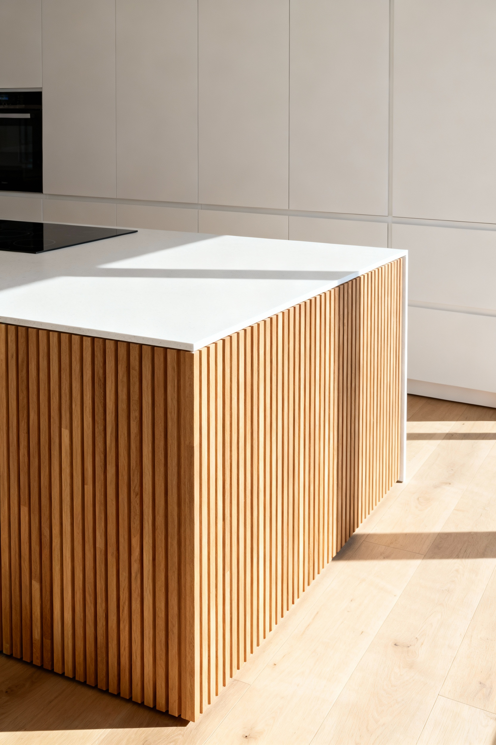 A minimalist Scandinavian kitchen featuring a large island clad in vertical natural oak wood slats, demonstrating textured overcladding used as a focal point to achieve architectural depth on a budget.