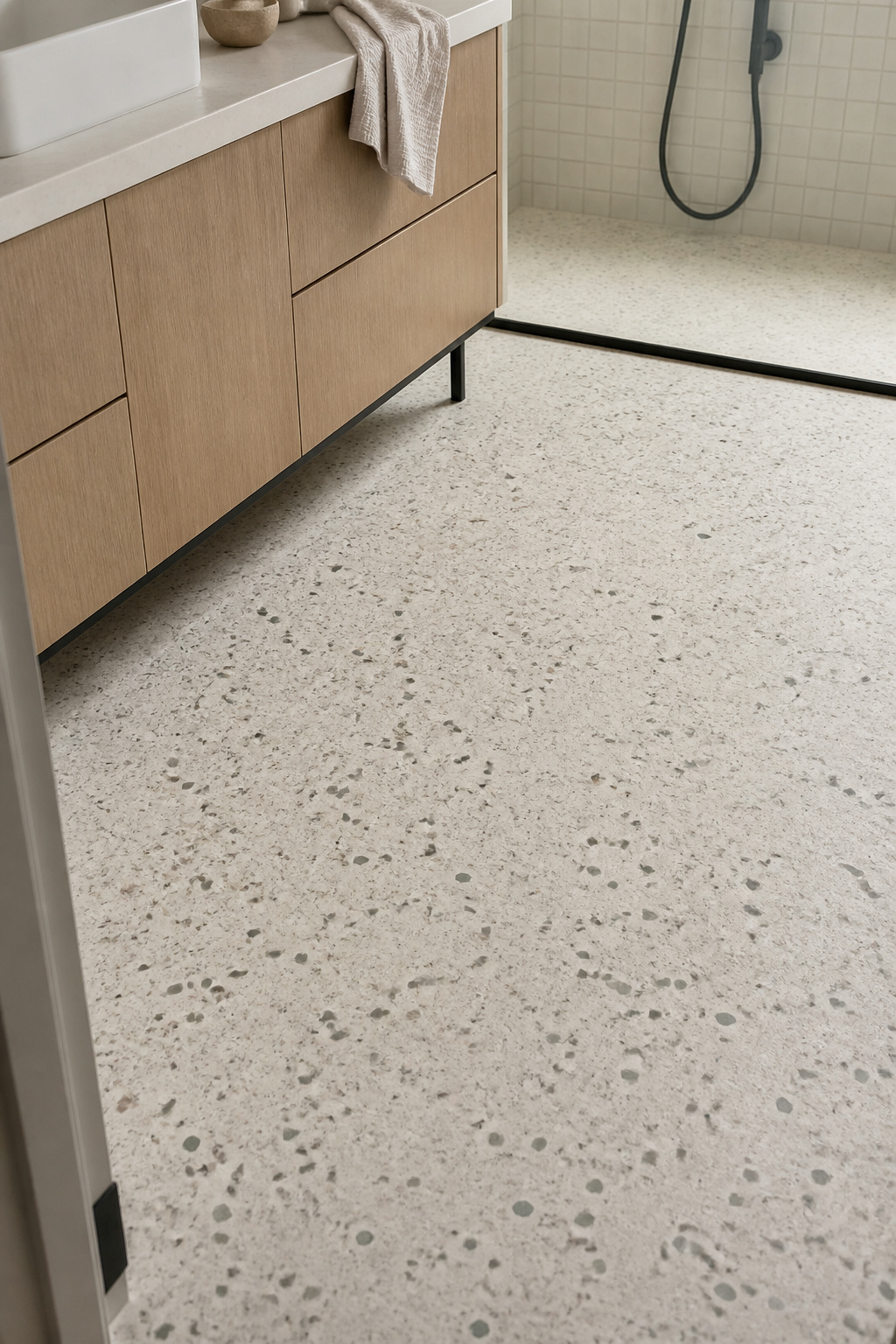 Honed terrazzo in warm white with scattered marble aggregate gives this modern bathroom floor a material richness that plain tile cannot replicate. Terrazzo reads as modern because of its restraint. A pale grey chip in a warm white cement base, or a scattered terracotta and sage mix in a cream ground, brings colour and personality without disrupting the material logic of the room. It works particularly well where the bathroom floor is visible from the entrance — given a clear sightline, terrazzo holds its own as the room's first design statement.
