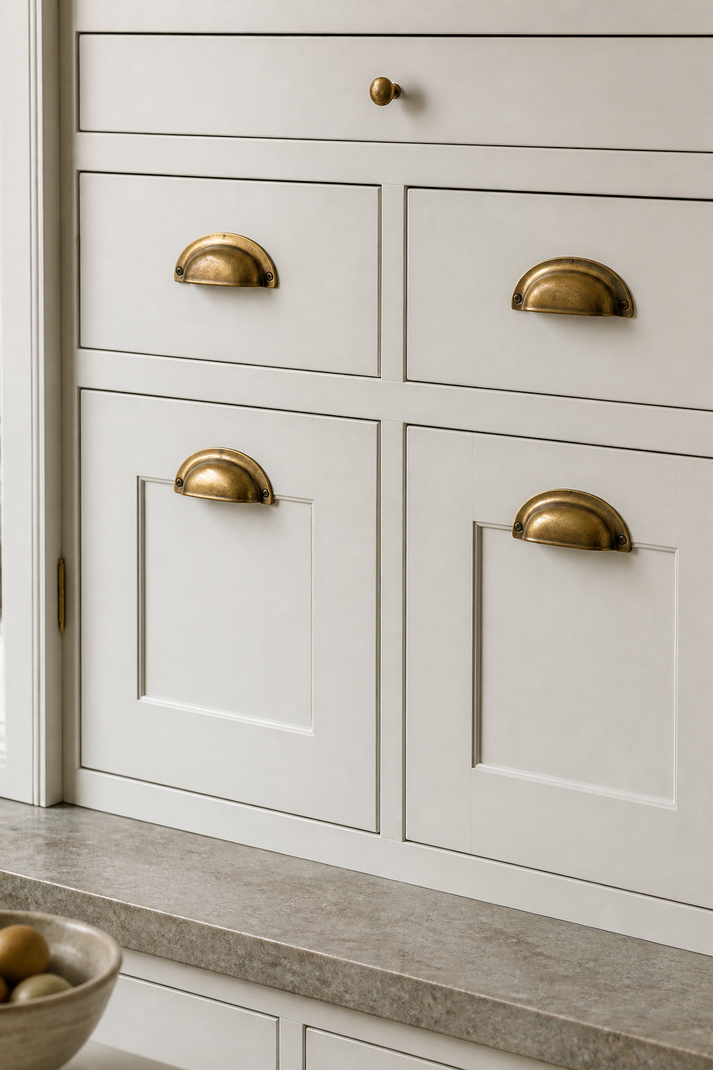 Unlacquered brass cup pulls on inframe cabinetry, the natural patina develops over 12–24 months and cannot be purchased ready-made, which is exactly what makes it worth specifying.