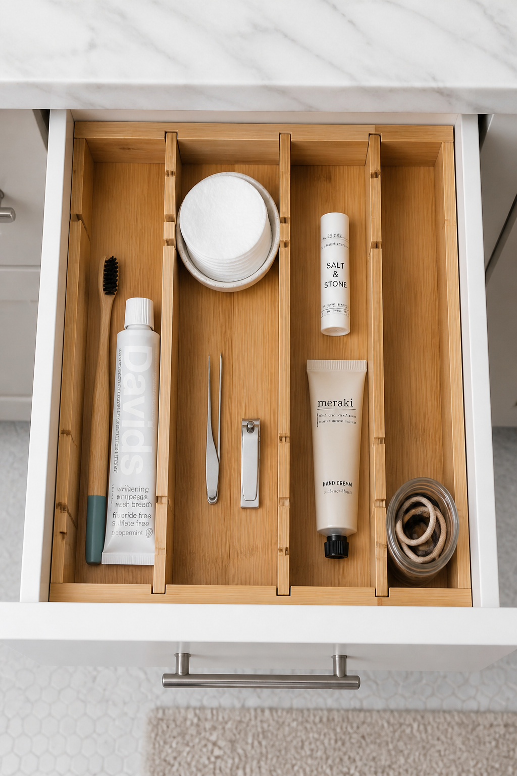 Adjustable bamboo drawer dividers transform a chaotic bathroom drawer into five clearly defined zones for daily essentials.