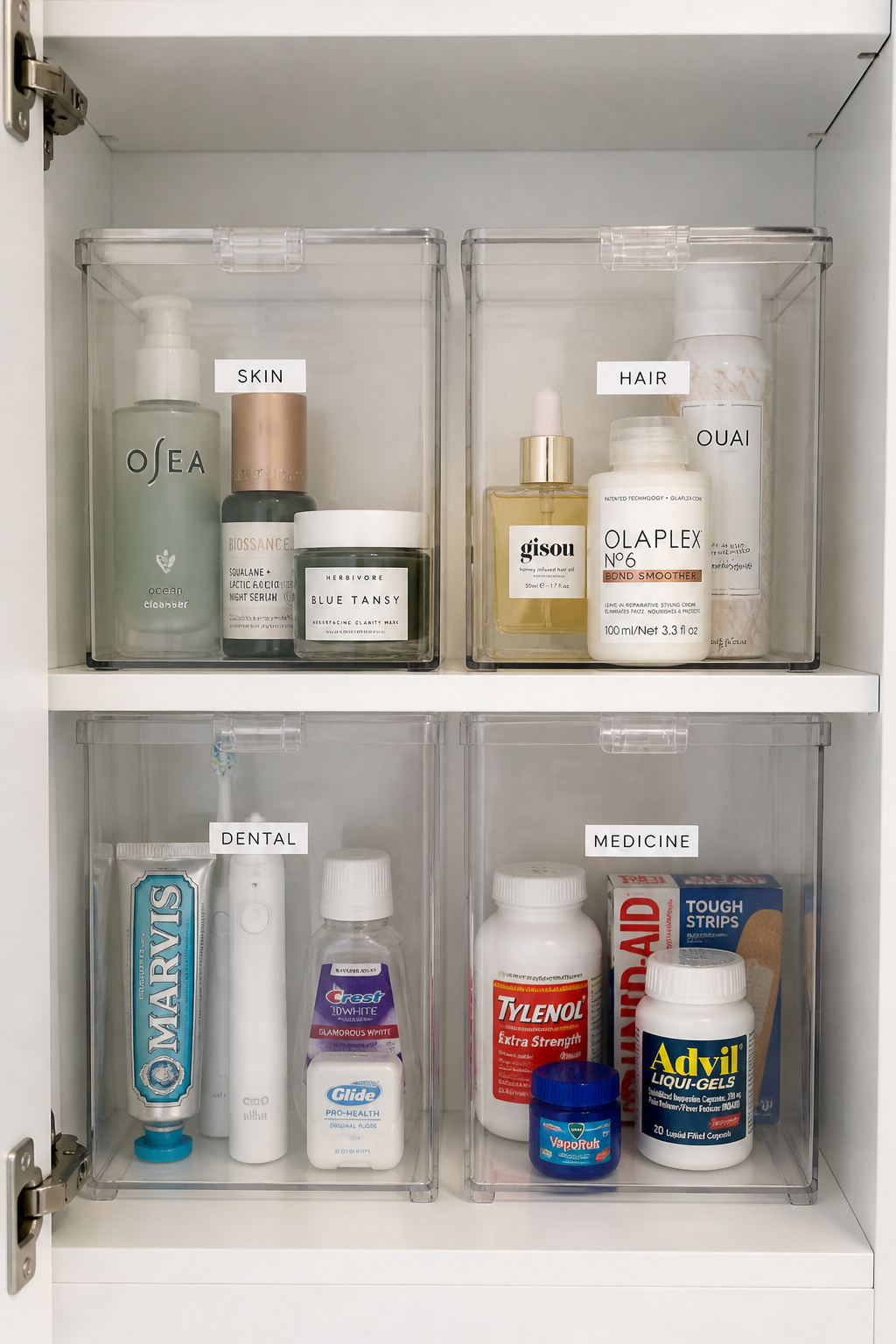 Clear hinged-lid stackable containers with minimalist category labels provide full visibility and easy access for bathroom cabinet organisation.