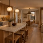 A Scandinavian kitchen at dusk, lit by frosted globe pendants, warm under-cabinet LED strips, and soft evening light — the layered lighting approach that defines Nordic kitchen design.