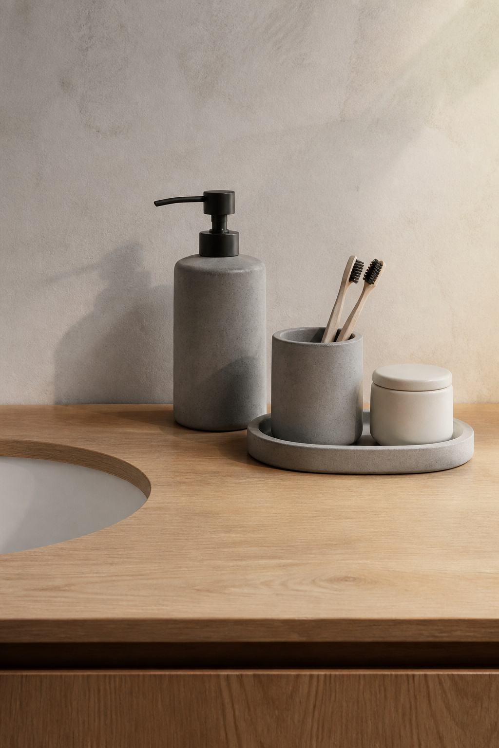 A set of hand-poured concrete accessories — dispenser, tray, and holder — creates a composed Nordic counter still life where material coherence does the decorative work.