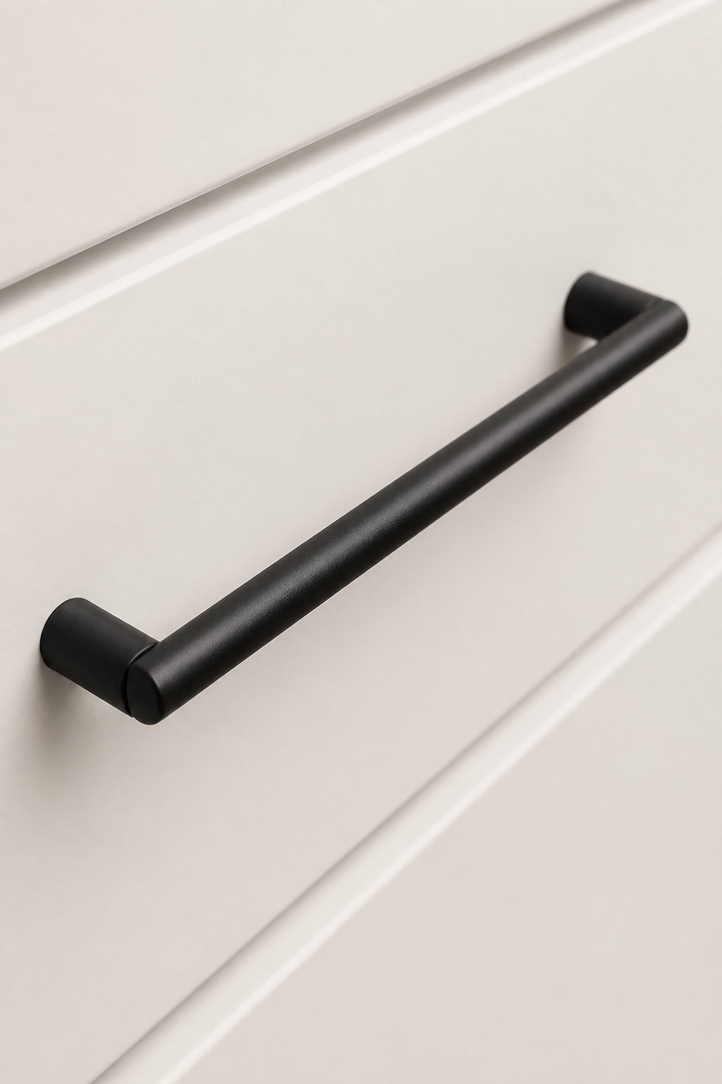 A 128mm matte black bar pull on warm white lacquer — the only reflective surface is the faint sheen of the metal's matte finish.
