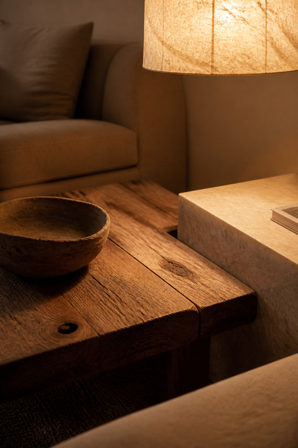 Reclaimed wood grain, travertine veining, and washi paper light — three honest materials in contrast that create a wabi-sabi living room corner worth sitting beside.