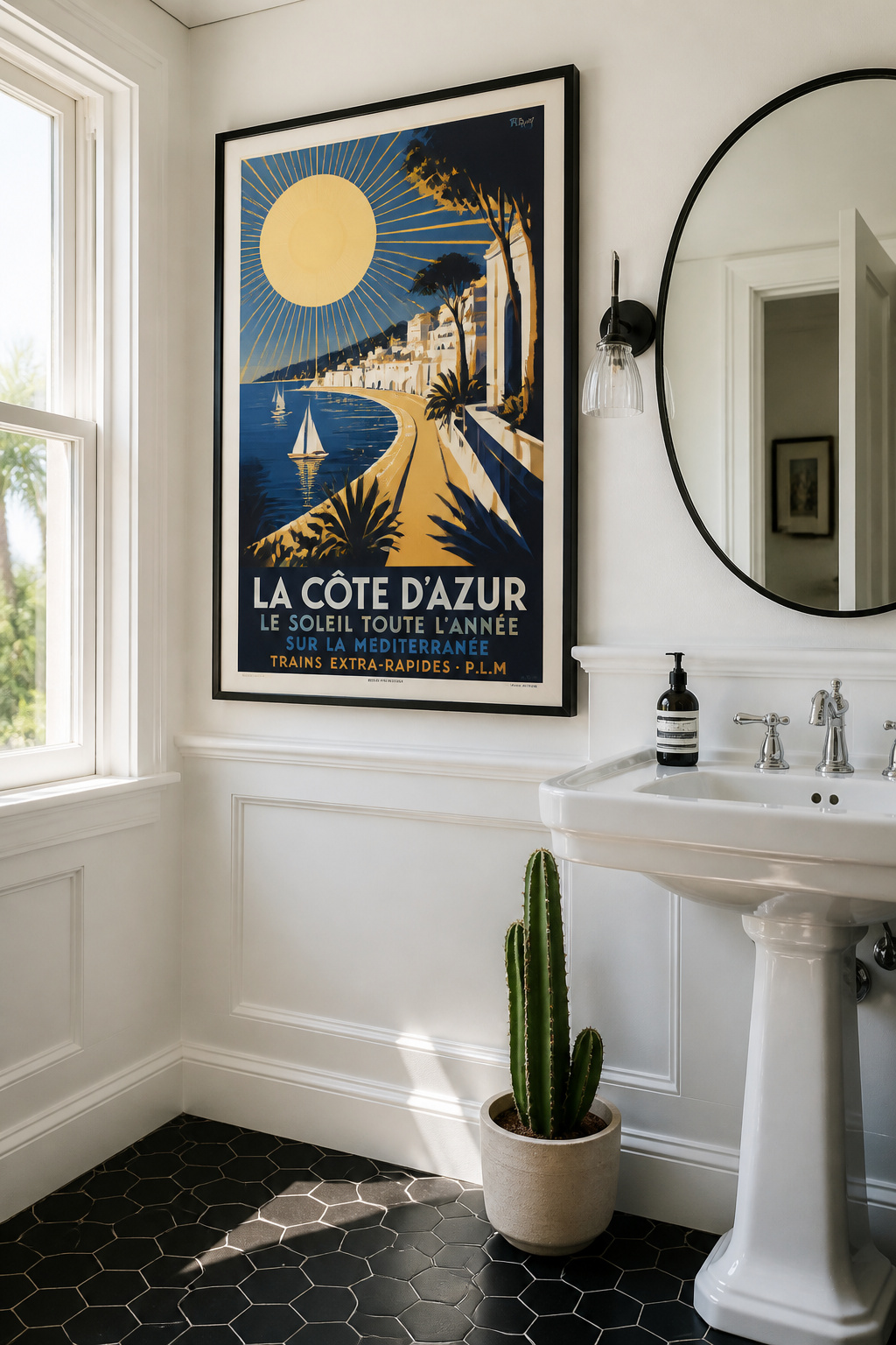 A bold Art Deco travel poster beside a traditional pedestal sink brings graphic confidence and a sense of escape to a classic bathroom.
