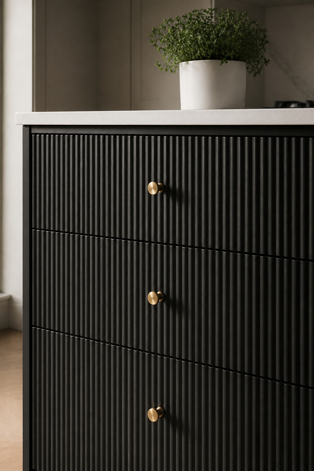 Fluted vertical-groove cabinet fronts on a slim black island — each groove deepens in shadow on a dark surface, amplifying the texture.