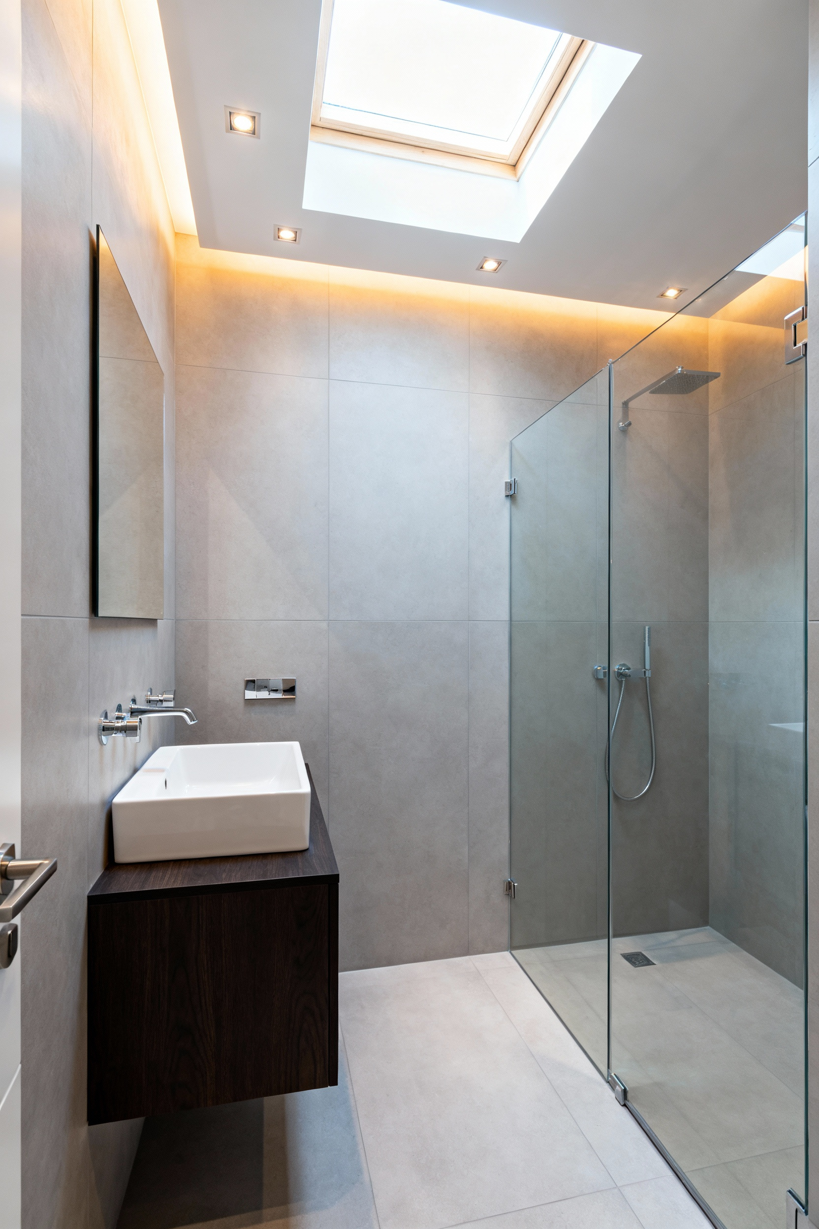 Small modern bathroom demonstrating an expansive look achieved by covering all walls and the ceiling with the same large-format light grey tile.