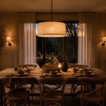 A beautifully layered dining room at dusk, lit by a warm linen pendant and wall sconces, showing how thoughtful dining room lights transform an everyday space into a welcoming retreat.