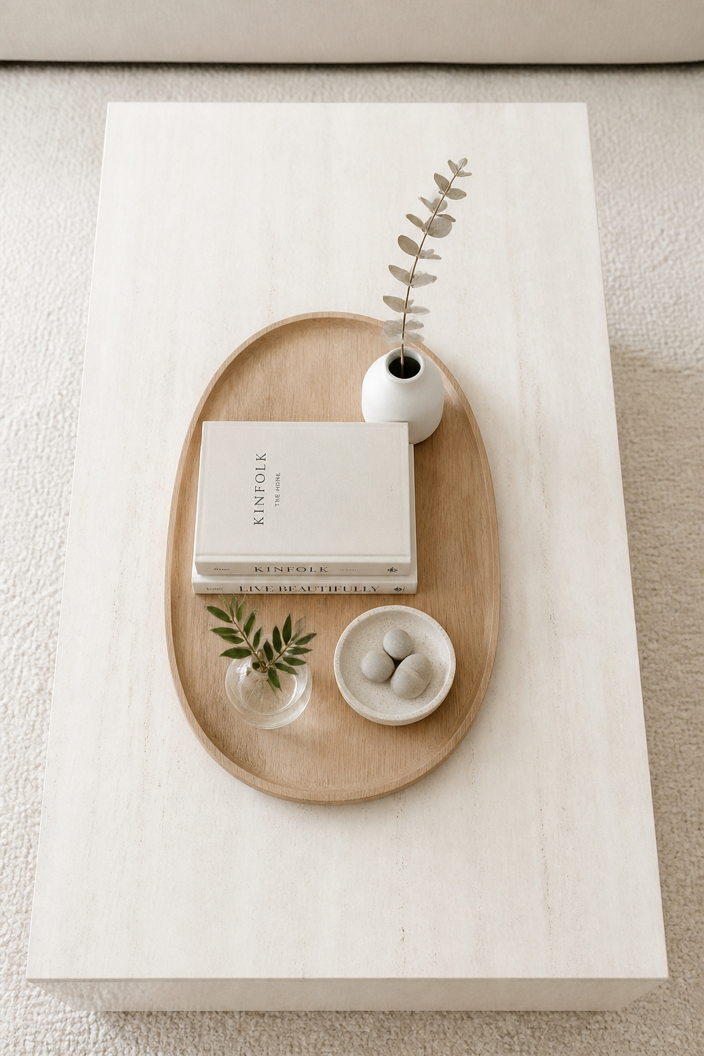 The five-object formula — tray, stack, vessel, organic element, personal item — gives every coffee table arrangement a clear structure that makes seasonal rotation effortless.