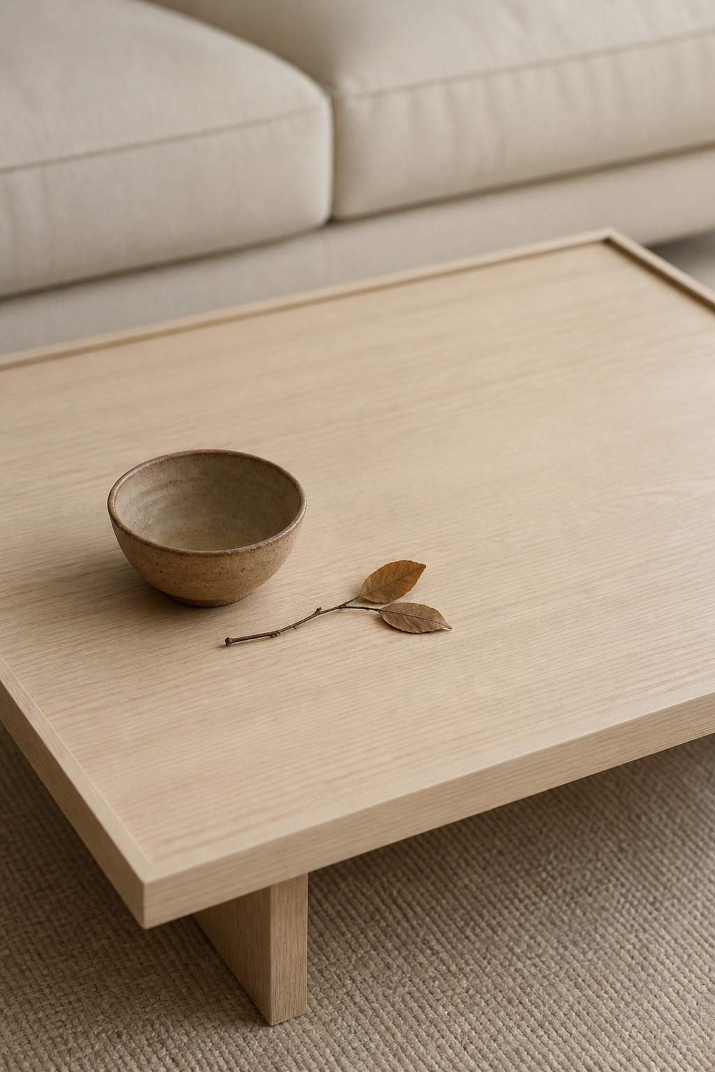 Minimalist Japandi coffee table styling uses the empty surface itself as a design element — one exceptional hand-thrown ceramic bowl, placed slightly off-centre, carries more visual weight than a dozen average objects.