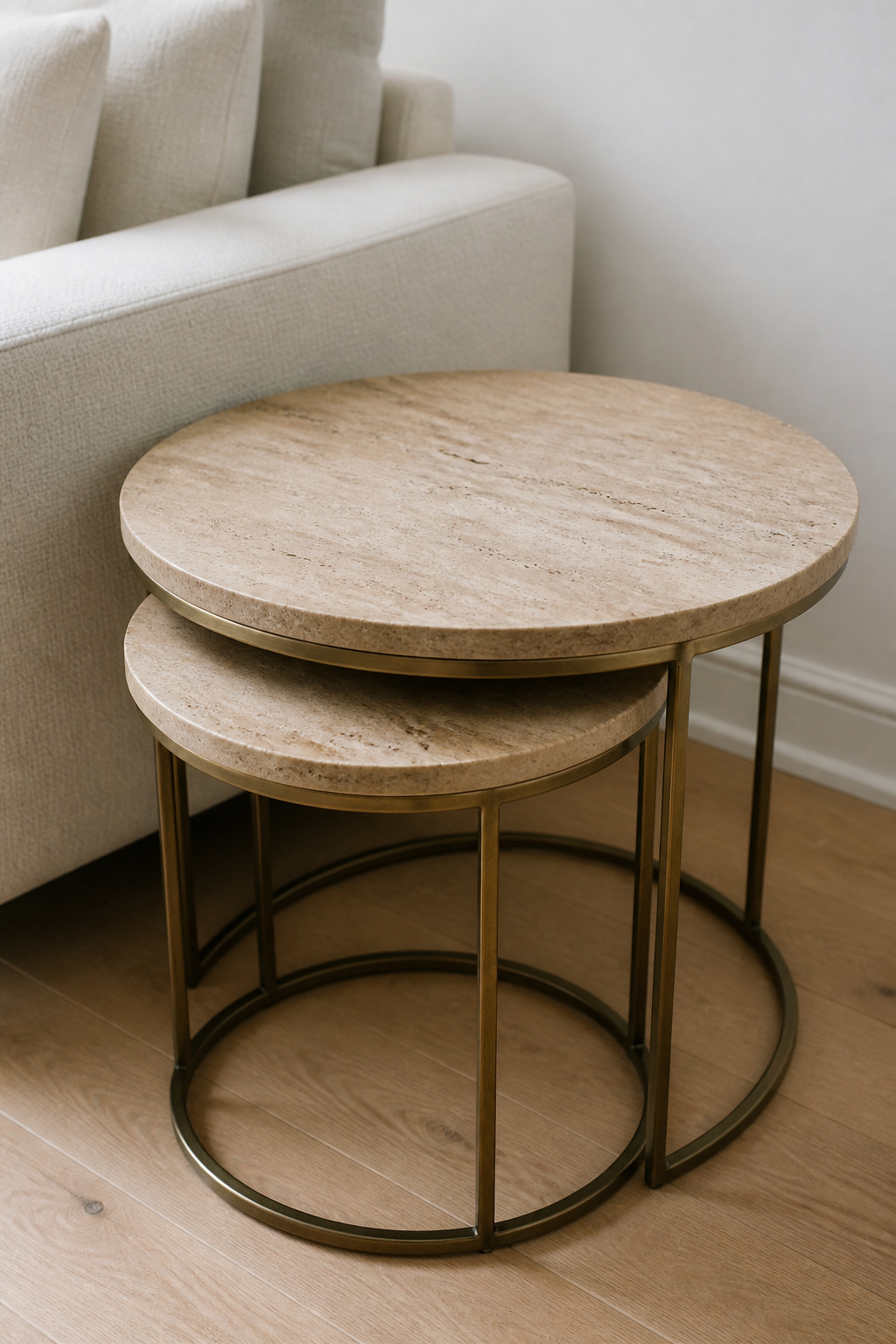 Round travertine nesting tables with brass frames store as one visual unit — organic stone and warm metal without any styling required.