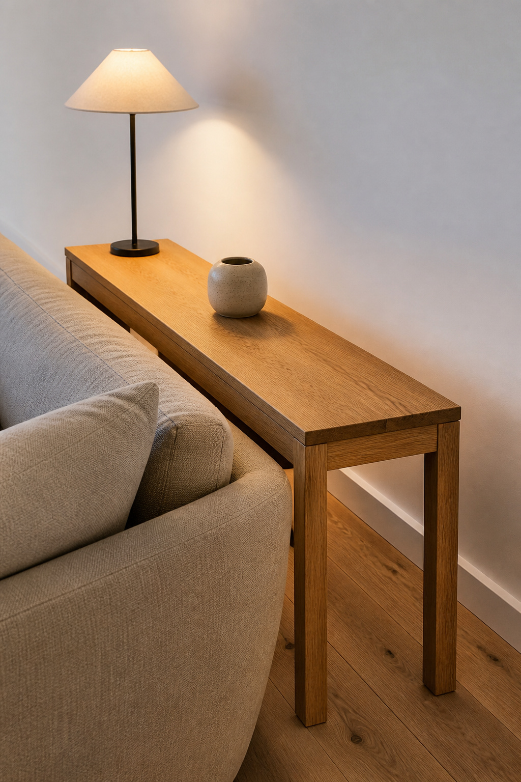 A slim oak console behind a floating sofa with one lamp and one object — the entire philosophy of considered minimalist living room furniture in one composition.