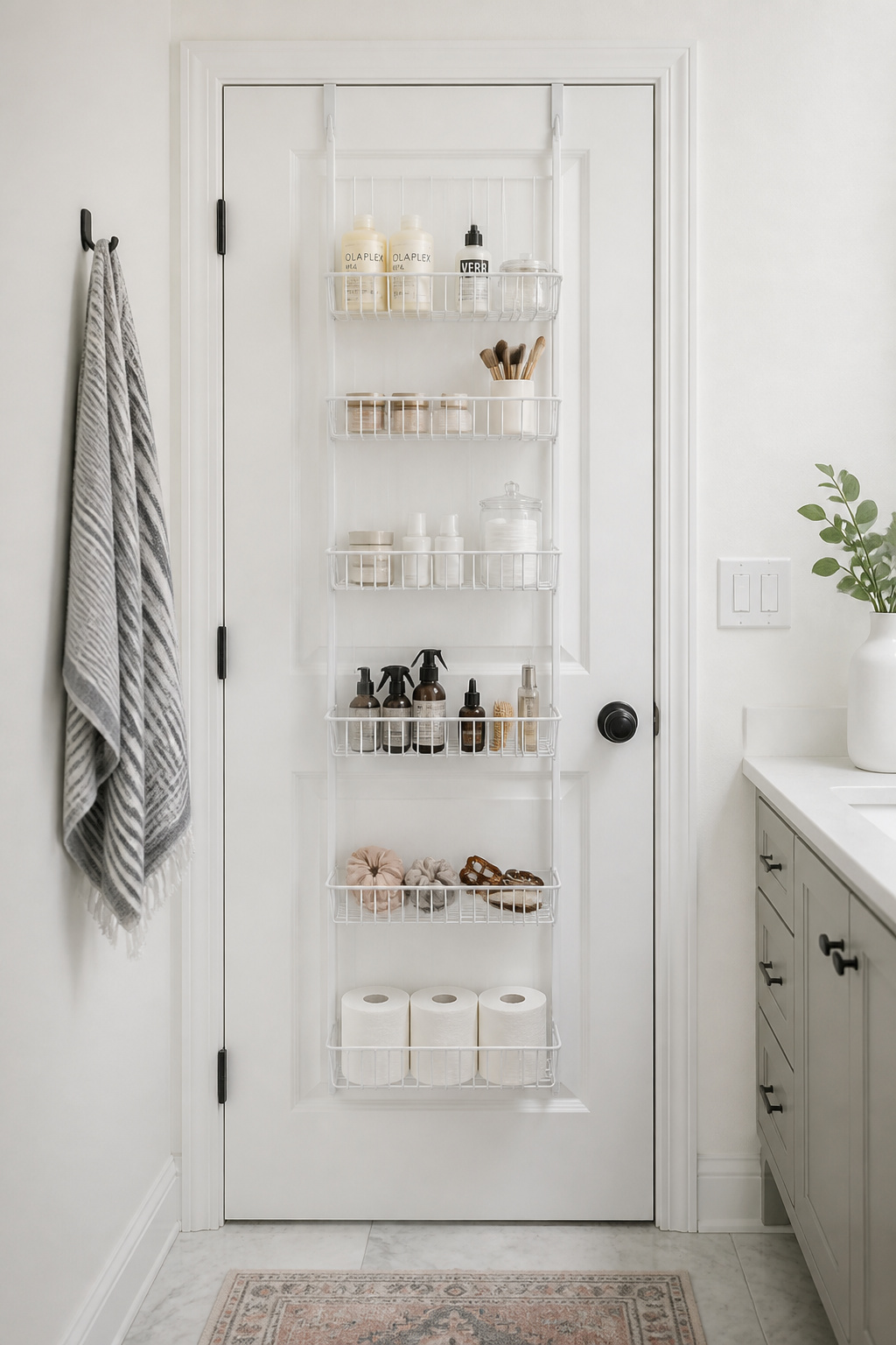 A powder-coated steel wire over-door organizer on the back of a bathroom door holds toiletries, cotton rounds, and accessories — a zero-drilling small bathroom storage solution.