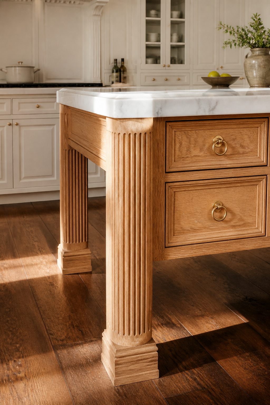 Furniture legs and fluted pilasters at the island corners convert a fitted kitchen from a utilitarian installation into something that reads as furnished.