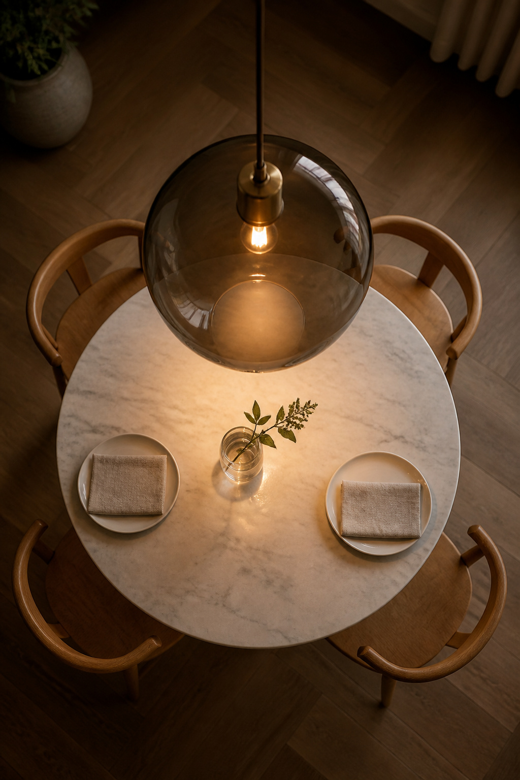 An 18-inch smoked glass globe pendant creates a warm amber halo over a round marble dining table — a natural pairing of circular forms and filtered light.