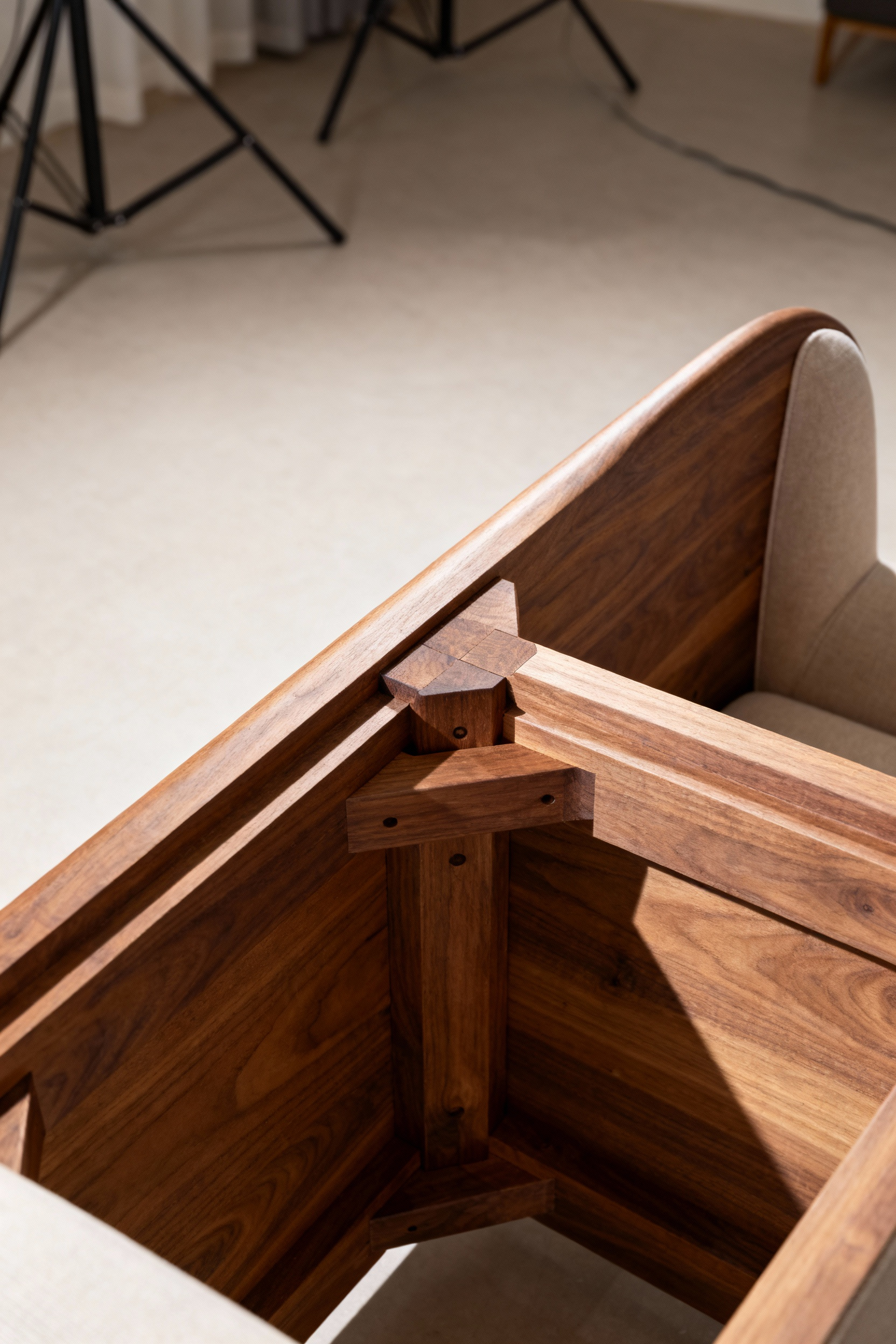 Detailed view of a modern living room chair's expertly crafted wooden internal frame, showing strong mortise and tenon joinery and fine wood grain, highlighting structural integrity.