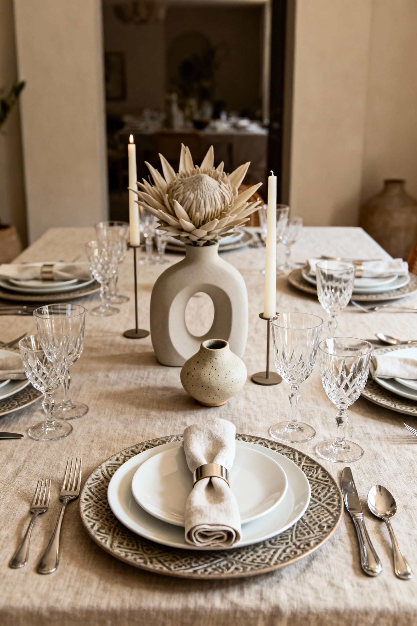 Elegant dining table set with layered textures, crystal, flowers, and candles, showcasing a sophisticated tabletopscape without people or text.