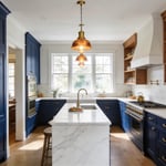 A modern kitchen with deep navy cabinetry, brass hardware, and marble countertops — the defining blue kitchen look that proves bold colour belongs in your cooking space.